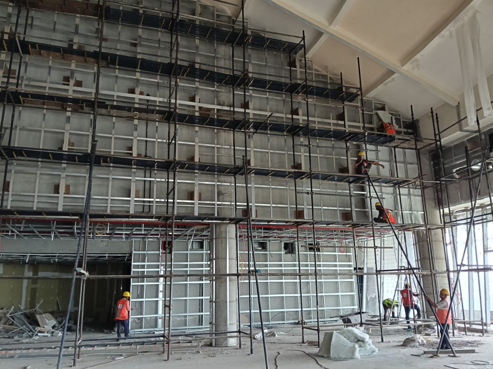 Workers installing a full-height metal framework on a commercial interior wall